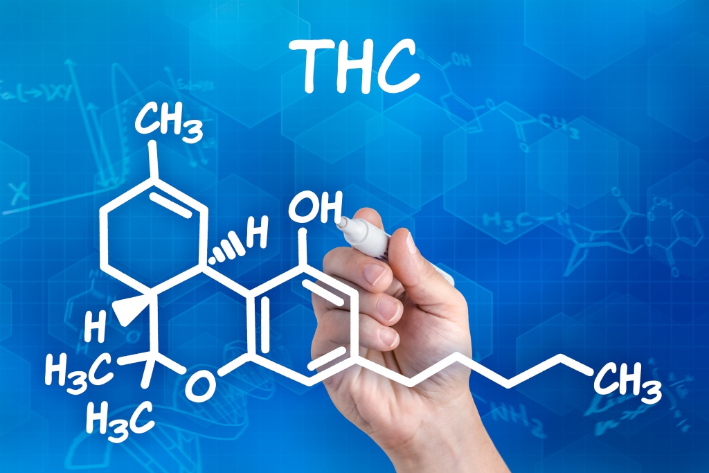 hand with pen drawing the chemical formula of thc