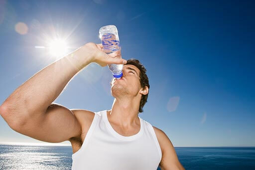 Man drinking bottle of water outdoors after workout