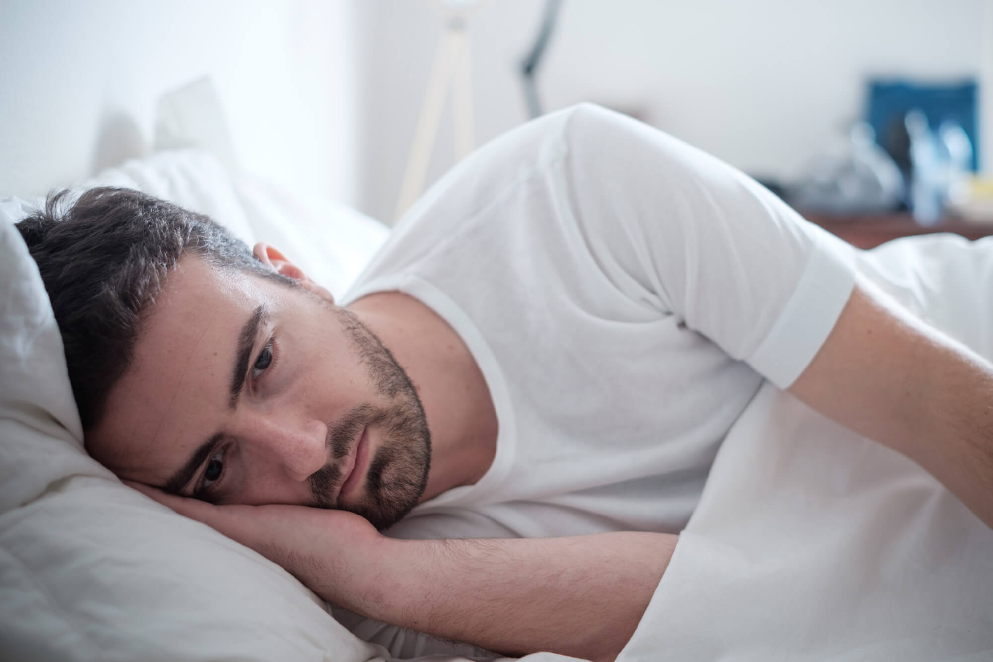 Depressed man lying in his bed and feeling bad