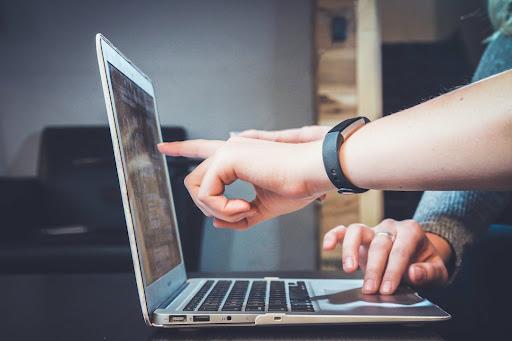 Two people's hands point at a laptop, looking at data from a treemap chart.